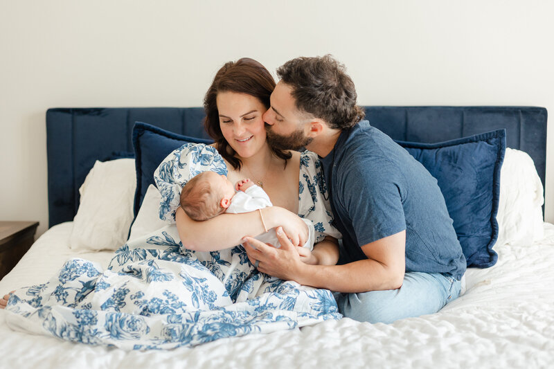Pregnant woman cradles her belly while looking down and smiling.