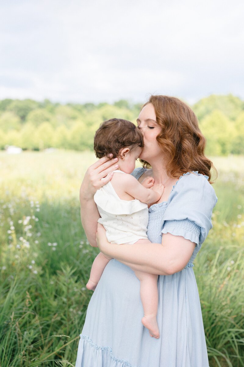 Family of three smiling in a green park during their family photos with missy marshall