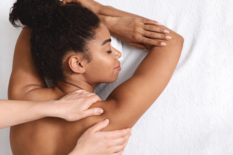 Woman enjoying a relaxing upper back massage, representing self-care and stress relief services.