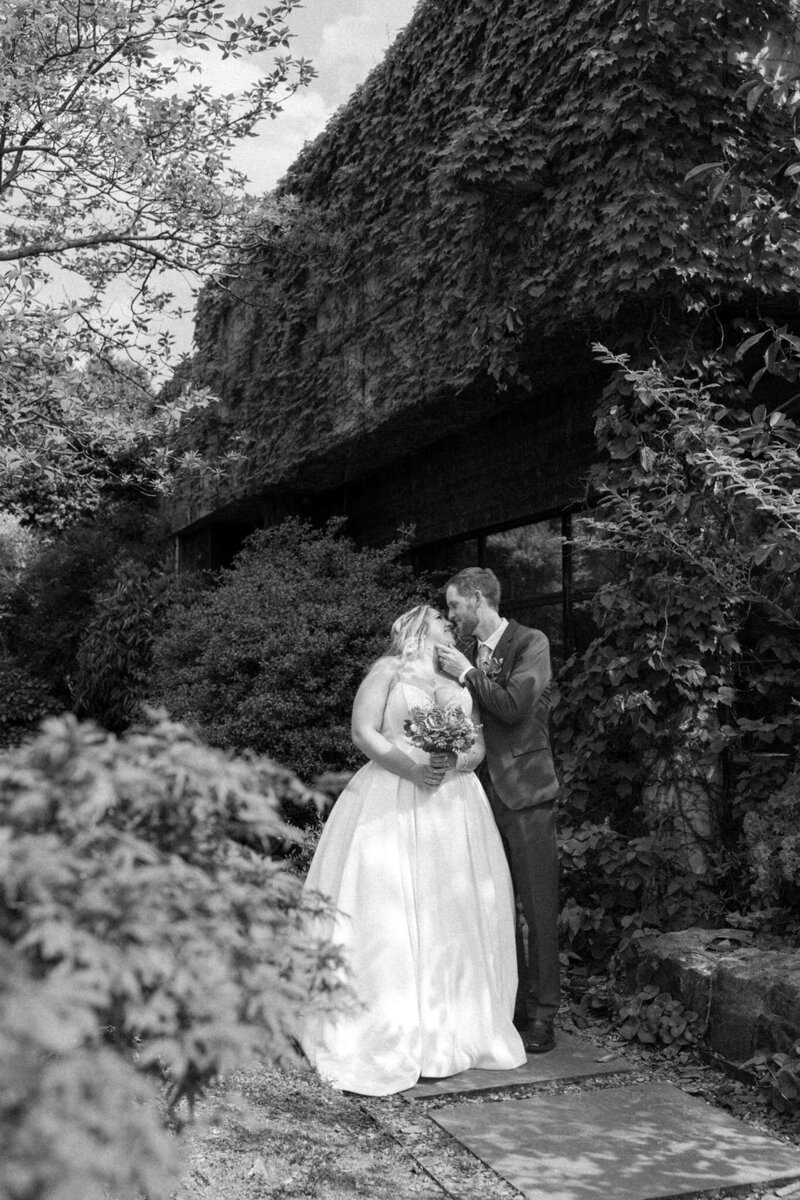 Black and white photo of bride and groom kissing