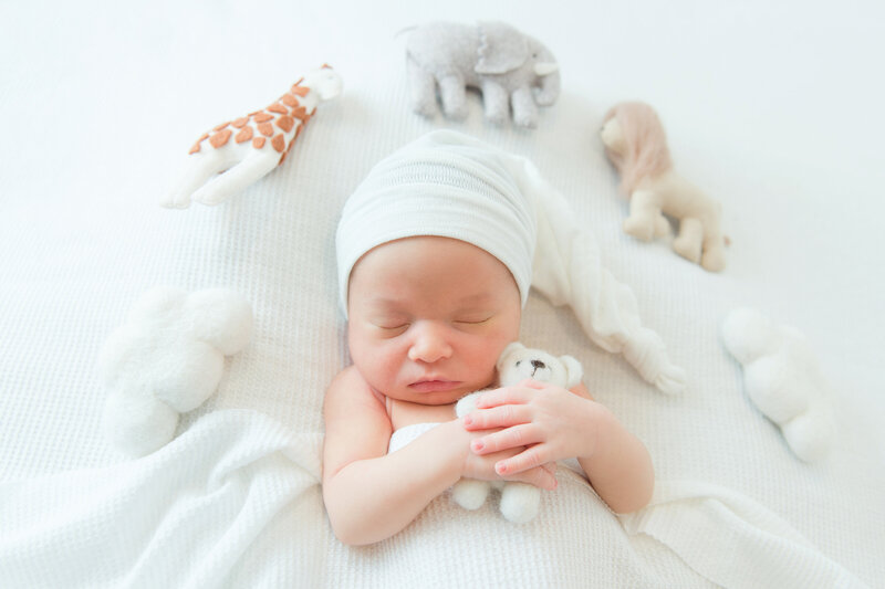 Newborn baby boy snuggling with teddy bear.