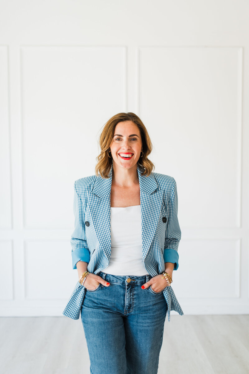 Business coach wearing blue blazer and jeans standing in a studio