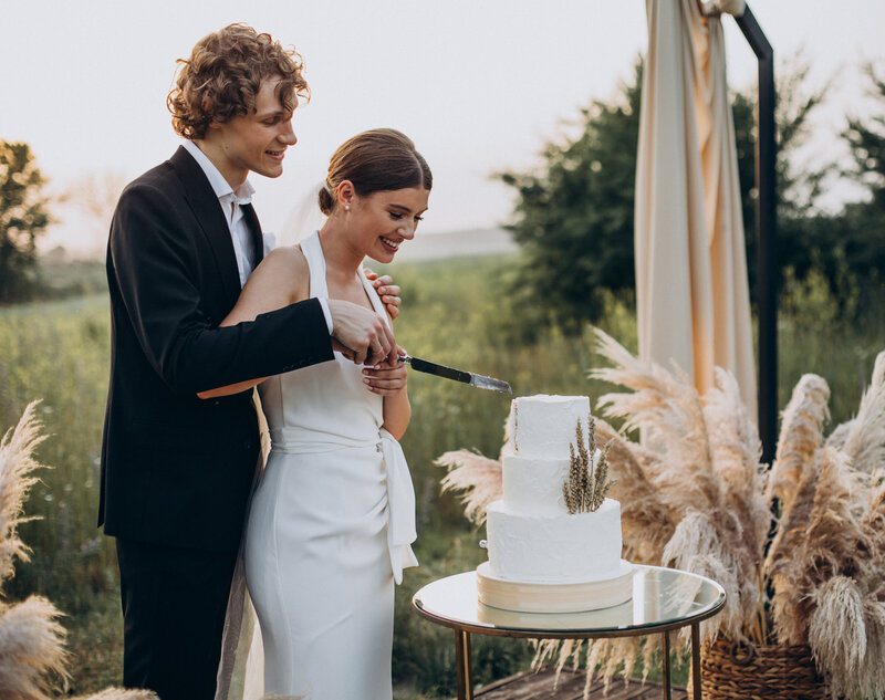 Mariés découpant leur wedding cake dans un décor naturel moderne et minimaliste. Organisation de mariage Vendée, Loire Atlantique, Nantes.