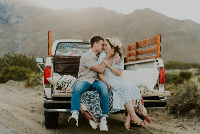 couple hugging in a vintage truck by the mountains