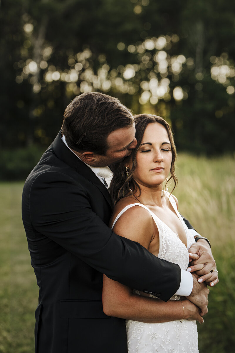bride and groom kissing with brides veil flowing in the wind