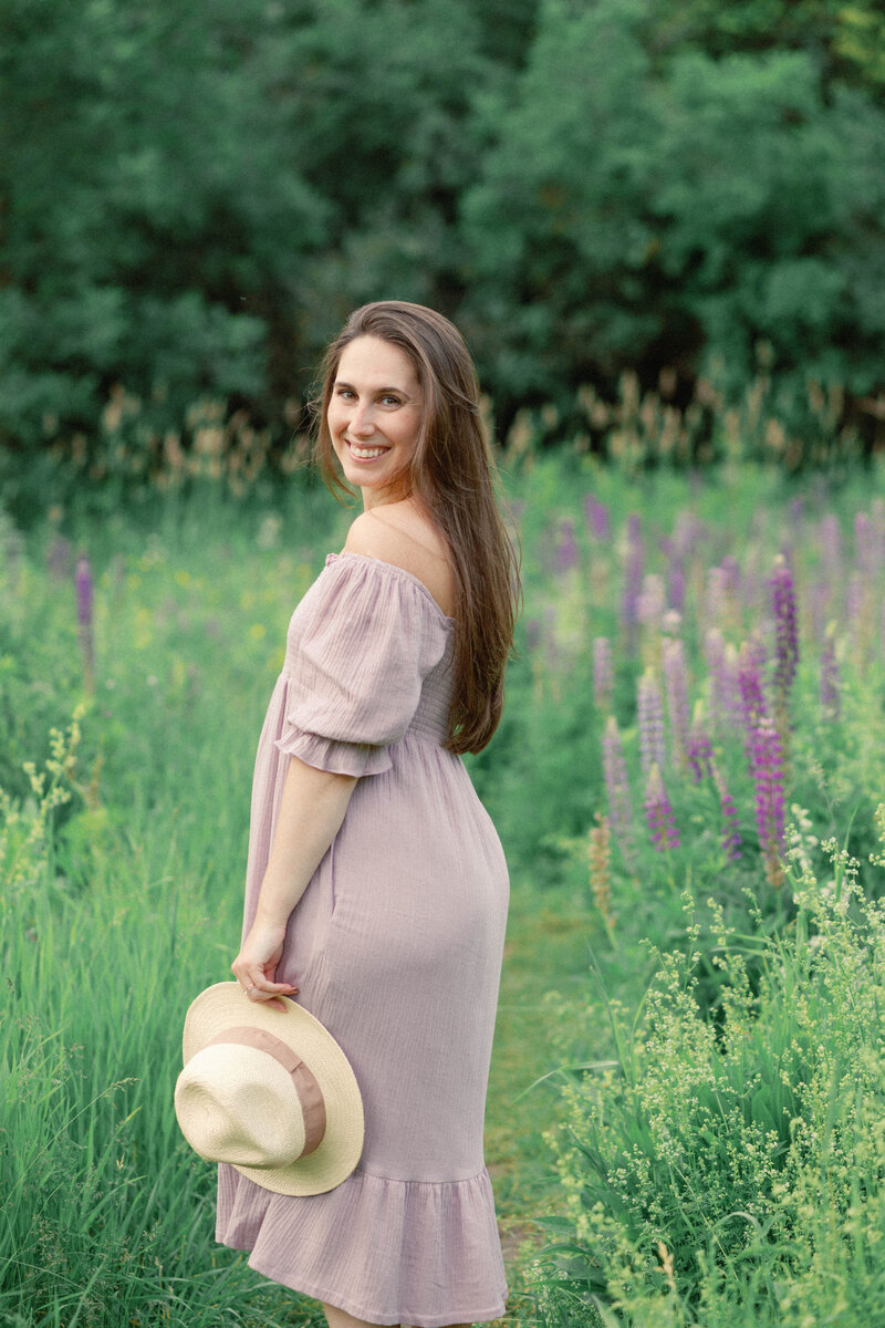 Brooke Lacombe standing in an outdoor lavender field holding hat