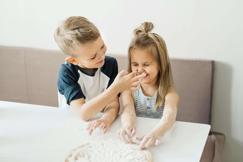 Young boy and girl baking with flour covered hands