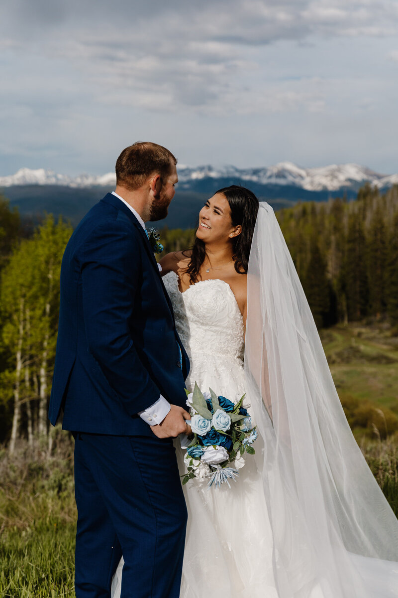 A wedding couple standing on a mountain overlook smiling