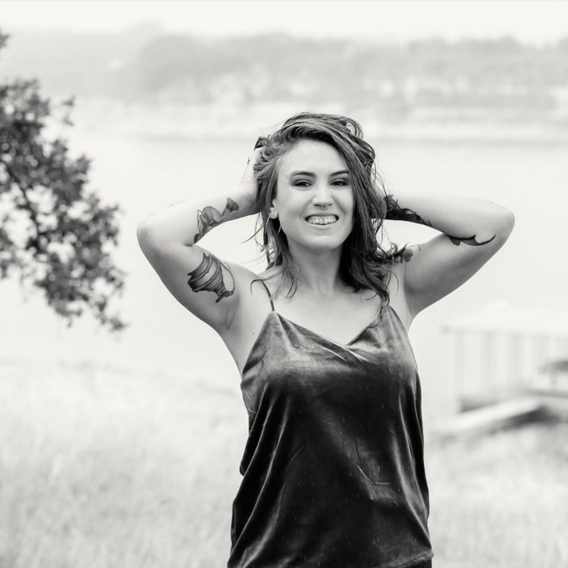 A black and white photo of Karla smiling with her hands in her hair.