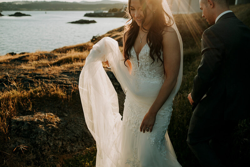A bride and groom wearing a yellow and green puffy jacket hold each other on top of Rainbow Glacier in Whistler. There is snow all around and blue skies.