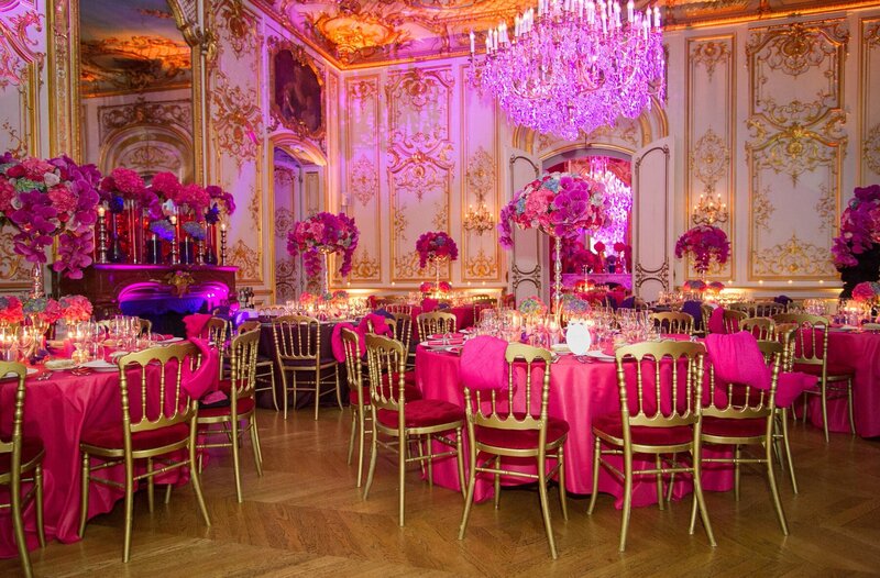 Large room set up with pink tablecloths and floral arrangements