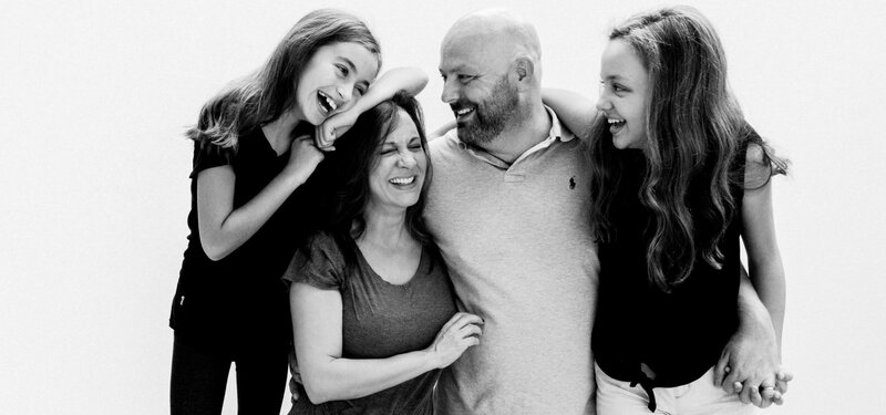 A man smiling with his wife and daughters.
