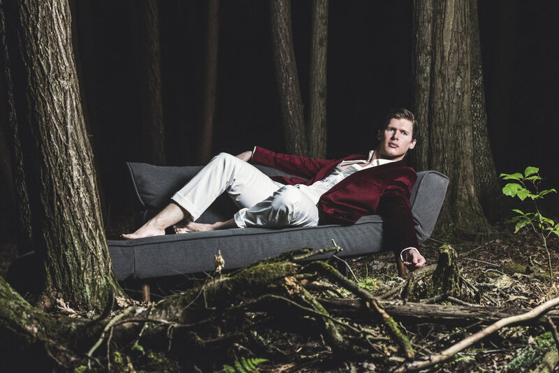 A person laying on a couch in a suit in the woods