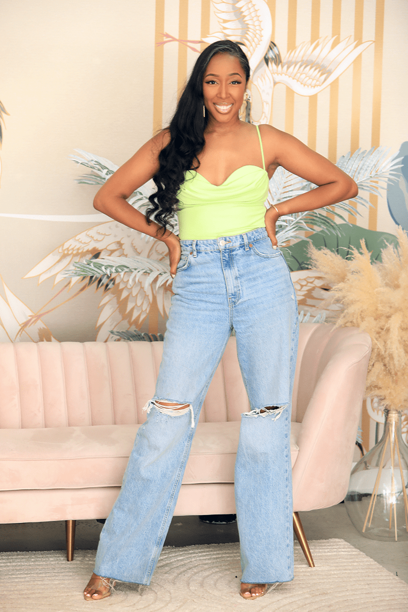 Woman in green top and ripped jeans standing