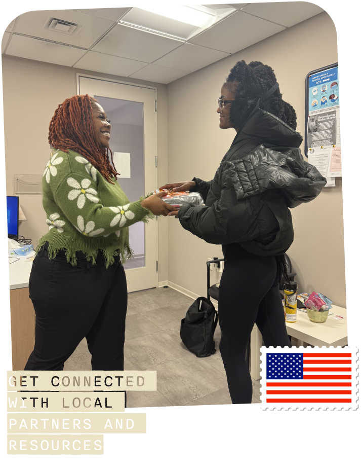 woman handing another woman a plate of food in an office