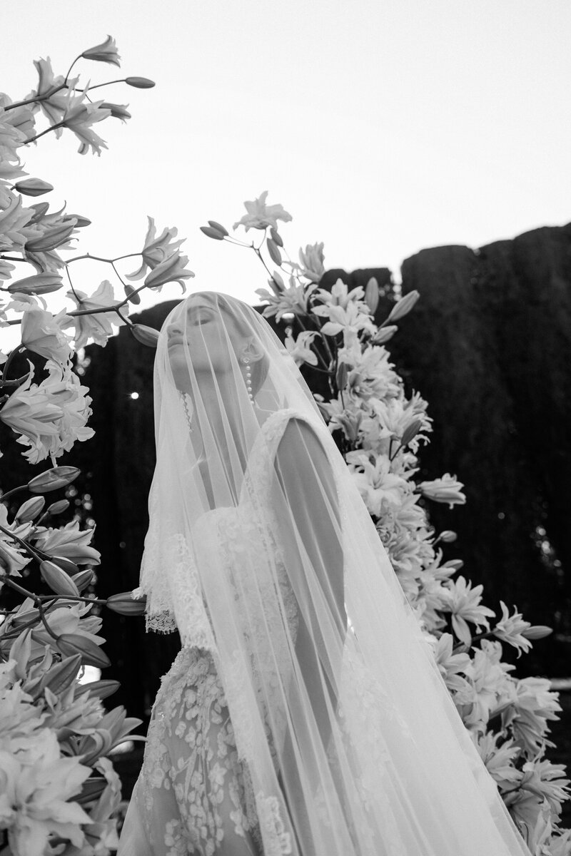 Bride between white florals with the vail covering her face in Villa La Foce Tuscany.