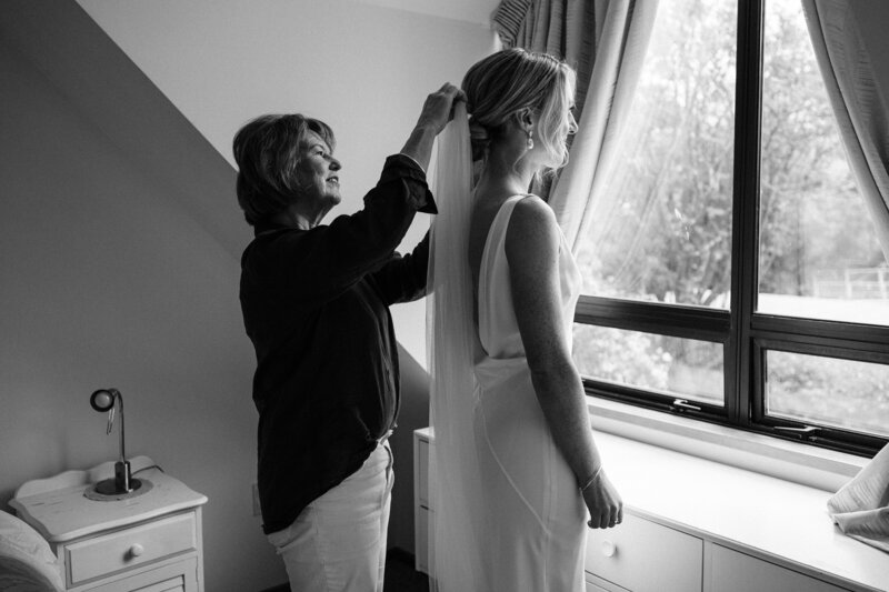 mother puts veil into daughters hair on wedding day morning in christchurch city airbnb