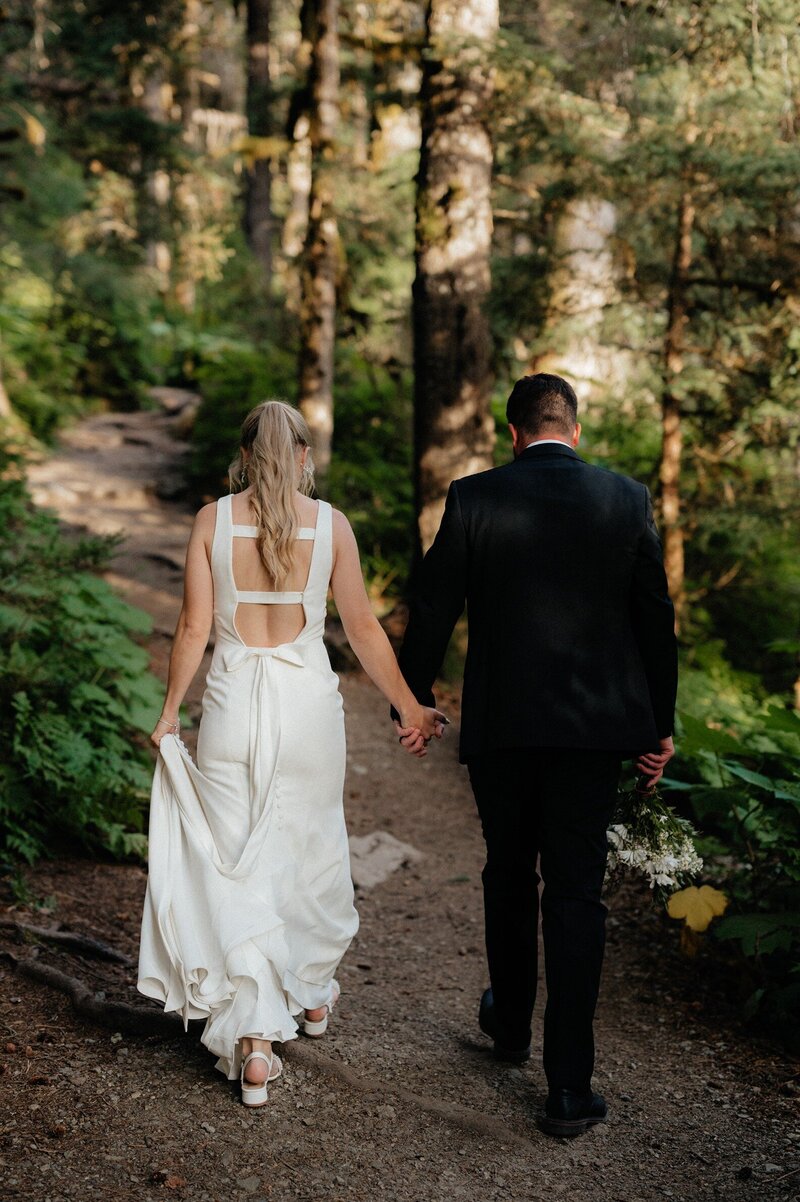 Bride and groom walking through the forest in Girdwood during their adventurous Alaska elopement.