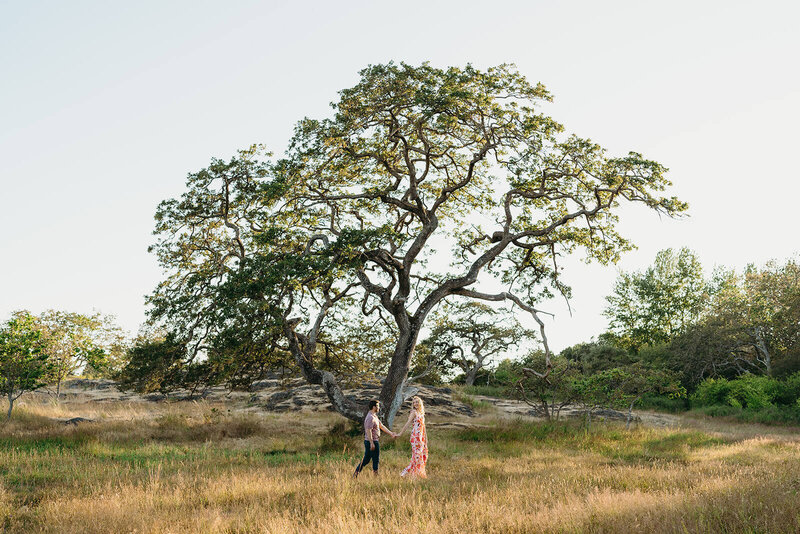 Couple walking by big tree during engagement photo shoot