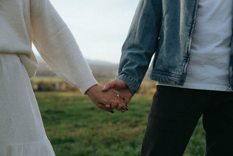 couple holding hands in field during vermont engagement photos, captured by Elsie Goodman, an NYC and destination engagement photographer