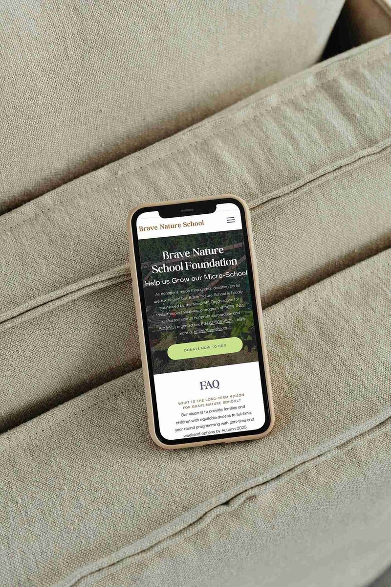 A phone placed on a soft couch, representing the blend of technology and relaxation at Brave Nature School.