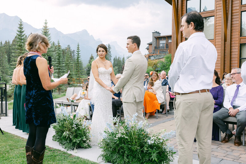 The couple stands together at the Malcolm Hotel, surrounded by mountain views, as they say their vows during an outdoor wedding ceremony.