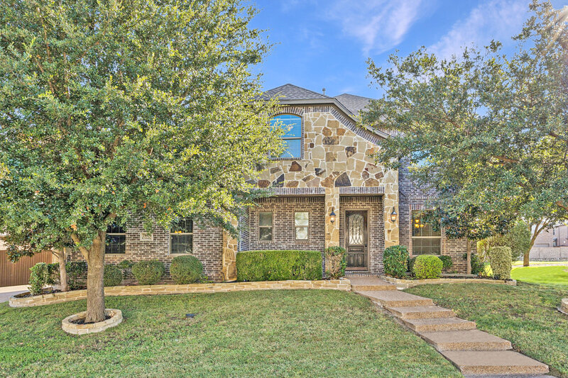 Stunning stone and brick two-story home with a welcoming front entry, lush landscaping, and timeless curb appeal. This beautifully maintained property offers classic architecture, mature trees, and a charming walkway. Perfect for families looking for style and comfort in a desirable neighborhood
