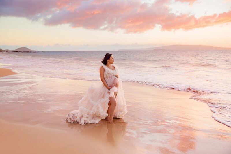 Woman in pink fluffy dress posing on the beach during Wailea maternity session