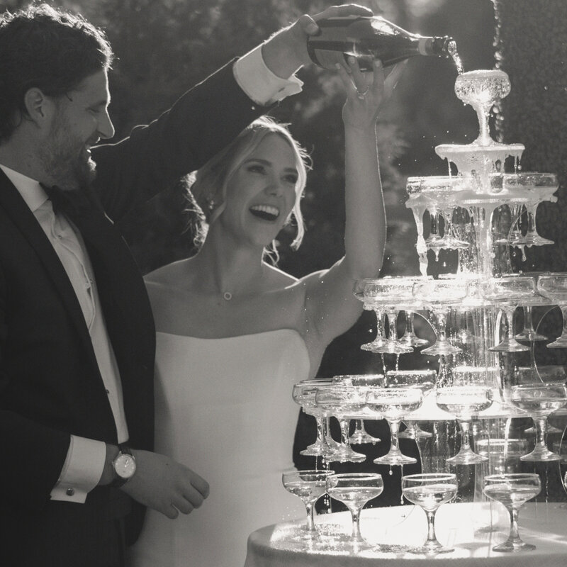The bride and groom hold hands together in the air and smile to their guests.