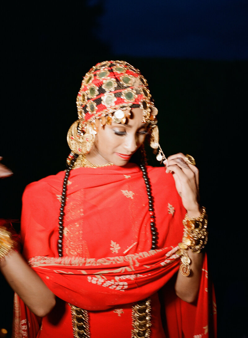 Sudanese bride wearing a vibrant red traditional wedding dress, adorned with gold jewelry and cultural elegance photographer Mo Davis