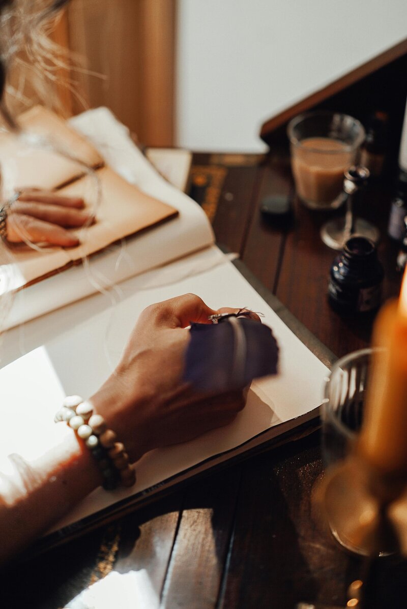 Woman's hands holding a pen over an open book