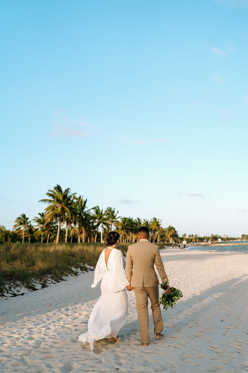 newlyweds walking away on beach