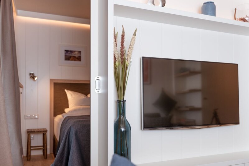 Ansicht vom Fernseher mit Blick in den Schlafbereich in einer Juniorsuite.