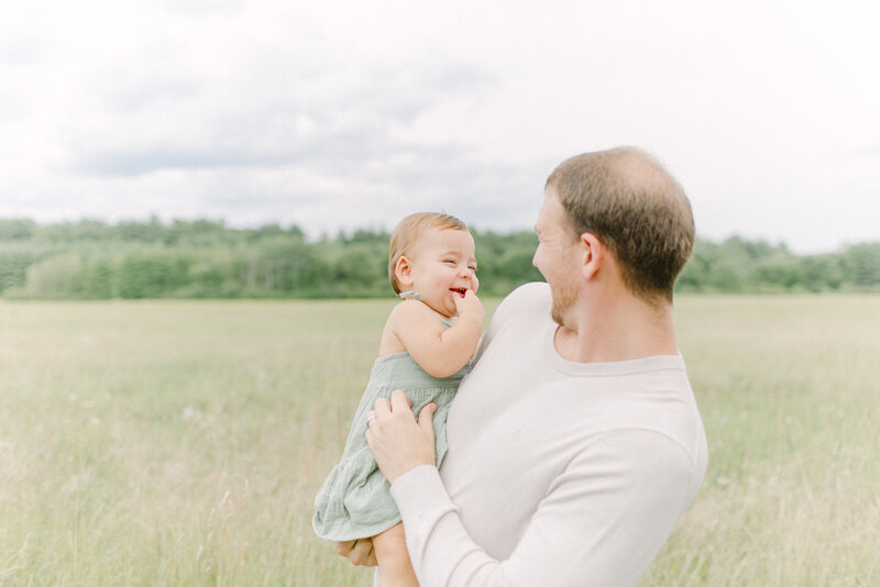 A young toddler is standing while holding each of his parent's hands