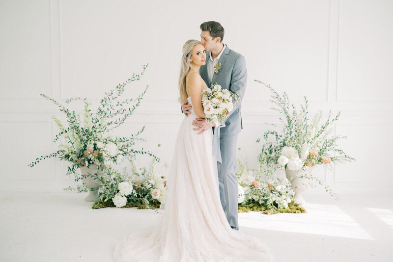 Bride and groom embracing in front of florals by chicago wedding planners.