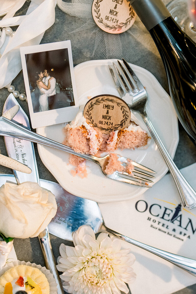 A beautifully captured detail shot from a California wedding, featuring a slice of cake, custom wedding tokens, and a candid Polaroid. The combination of delicate florals, personalized details, and a shared moment between the couple reflects the romantic and intimate nature of a coastal California wedding. Perfect for couples looking for inspiration in creating a personal and unique wedding experience.