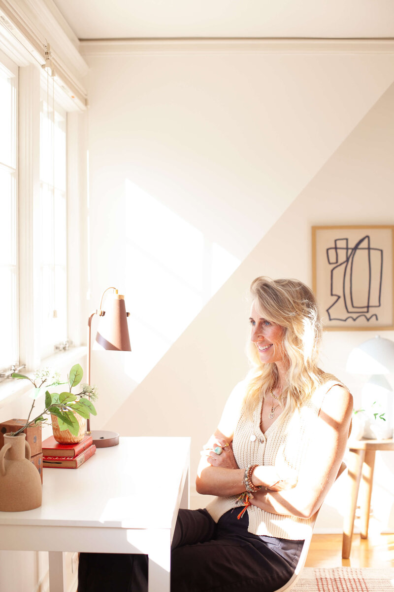 Stephanie a realtor in portland sits in front of a white table with her arms crossed.