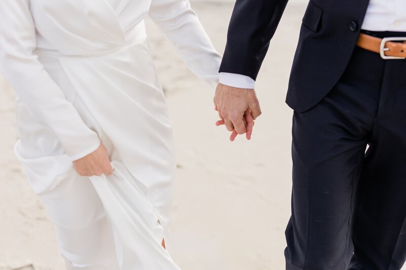 Bride and groom holding hands on the beach at the peter shields inn