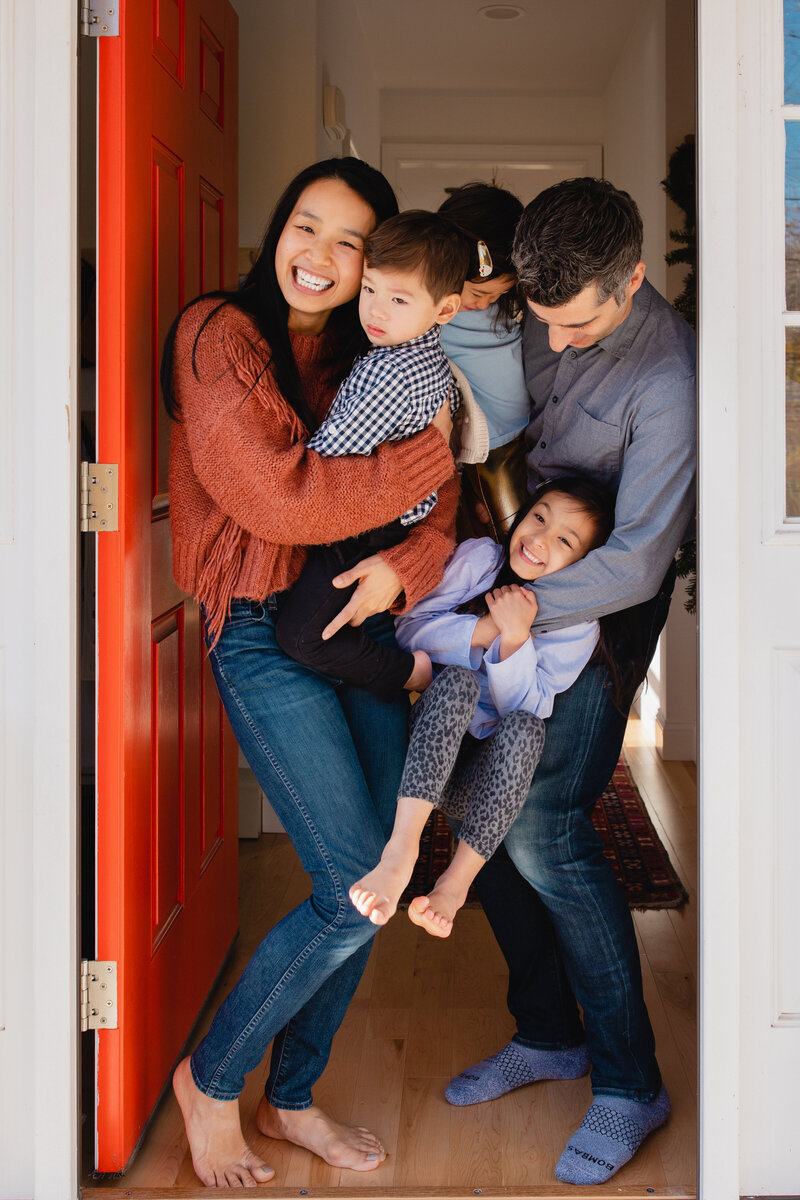 Family Photographer, a small young family huddle and snuggle together in a door well
