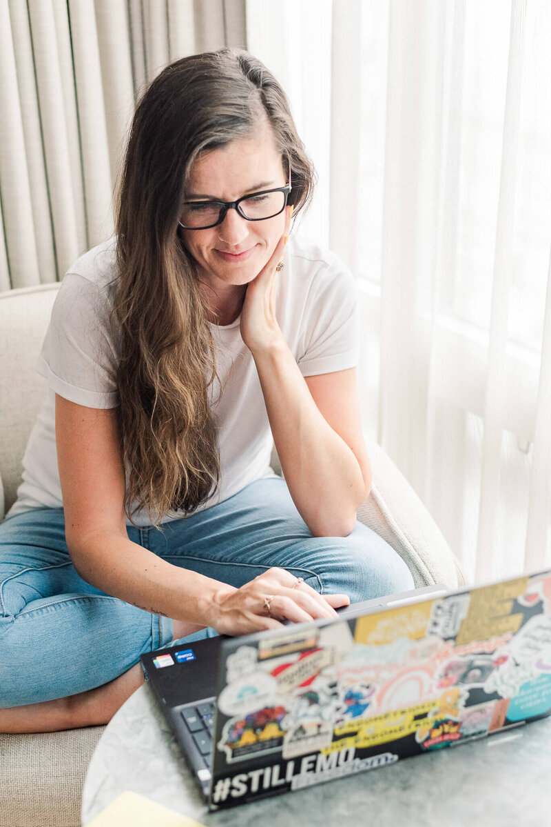 Wedding photographer working on a laptop at home, representing HoneyBook systems and workflows that simplify client management and reduce overwhelm.