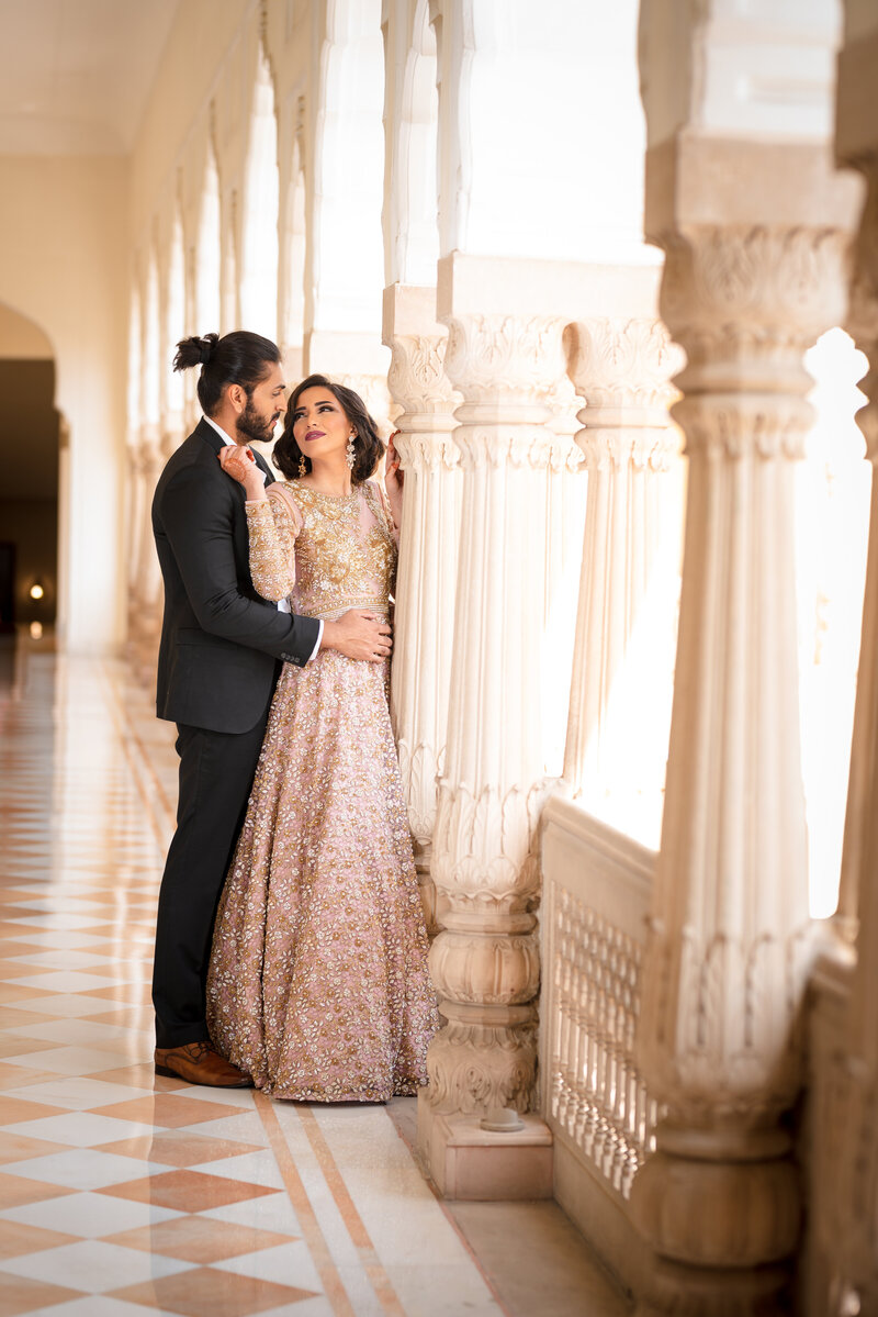 sikh couple wearing black and orange looking into each others eyes smiling