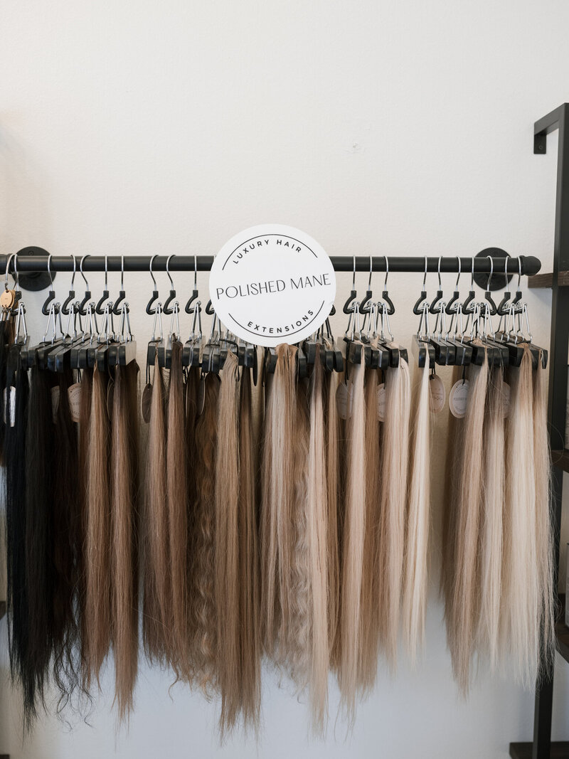 hair stylist holding up hair extensions to clients hair for matching