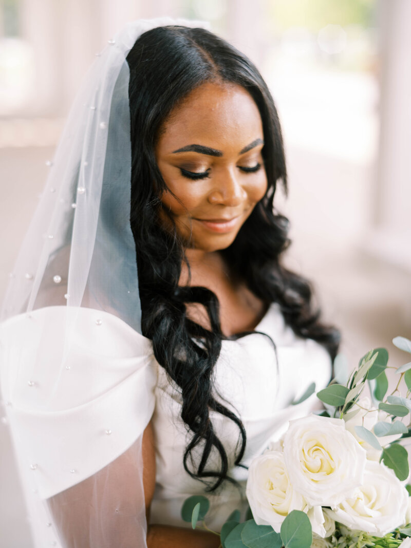 a black bride looking down at her white flowers by colorado wedding photographer jkg photography