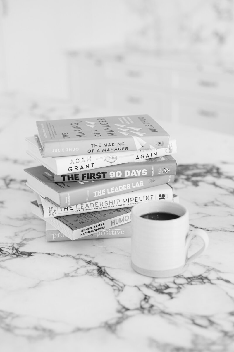 Professional leadership and development books displayed alongside a cup of coffee