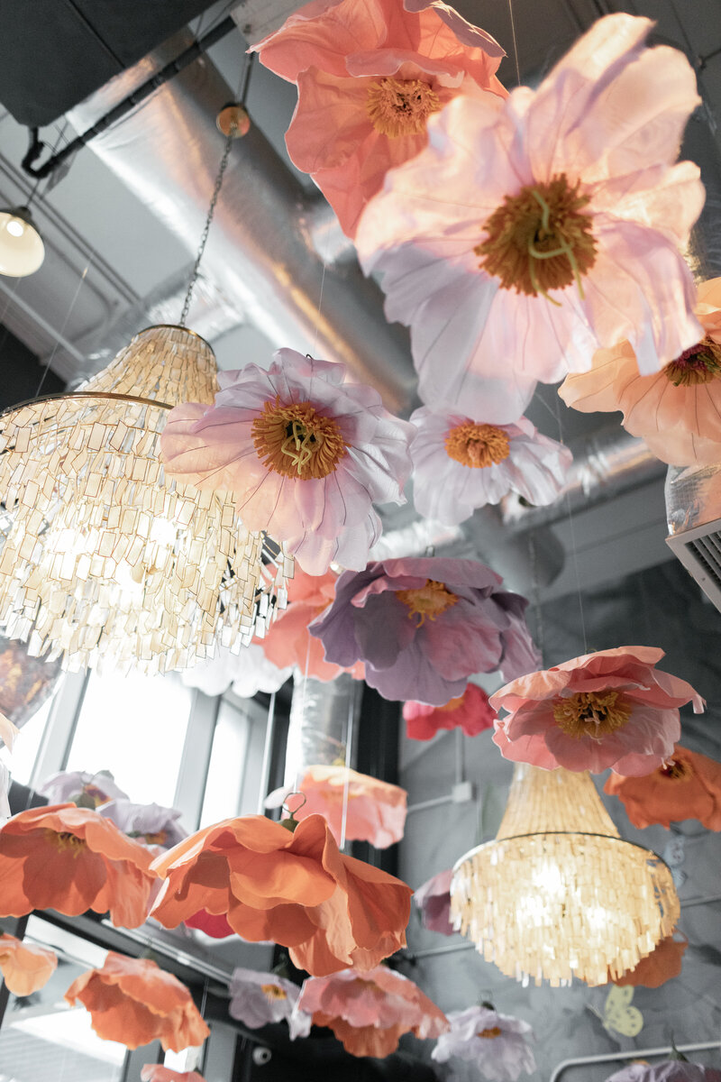 mix of paper mache florals, silk florals, and crystal chandeliers installation in modern industrial entry way
