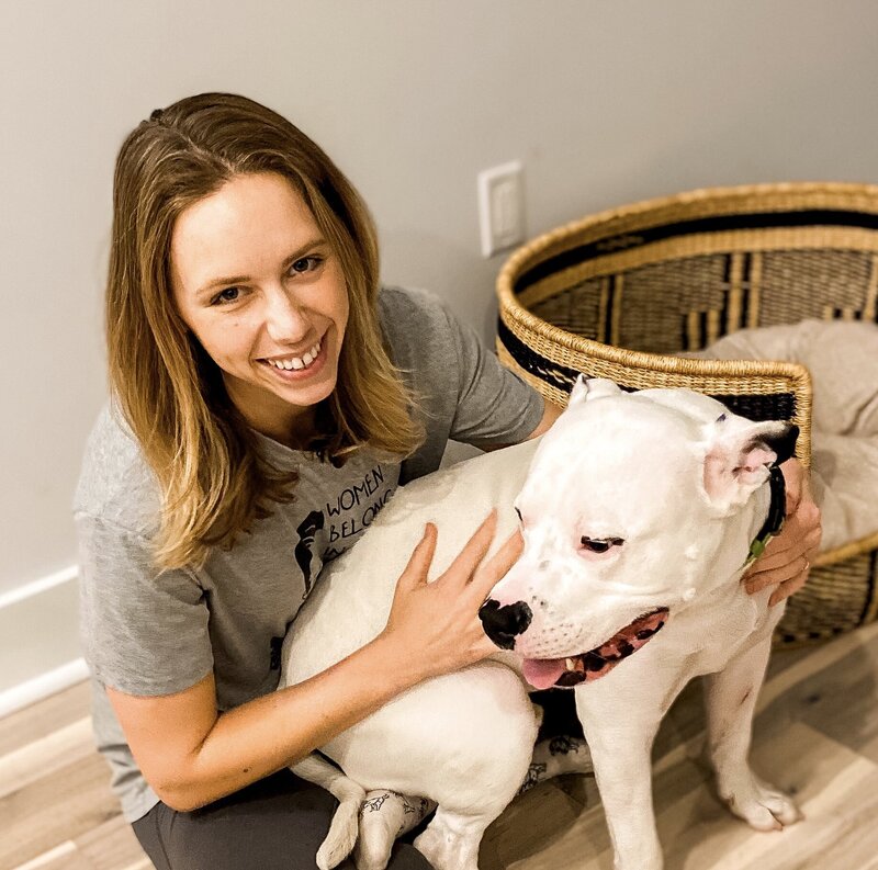 Dog trainer Michelle Pennarola sitting with a white dog