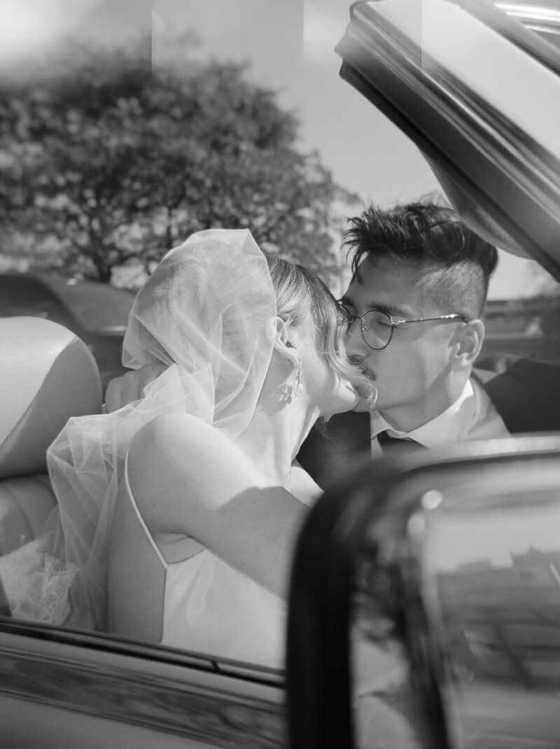 newlywed couple kisses in vintage mercedes convertible wedding getaway car, editorial film photographer in Detroit