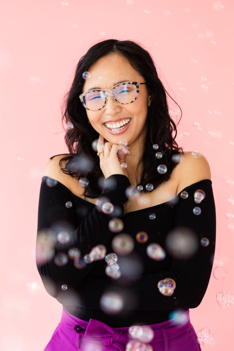 Anh Nguyen, NYC graduation photographer, smiling at the camera in a studio portrait.