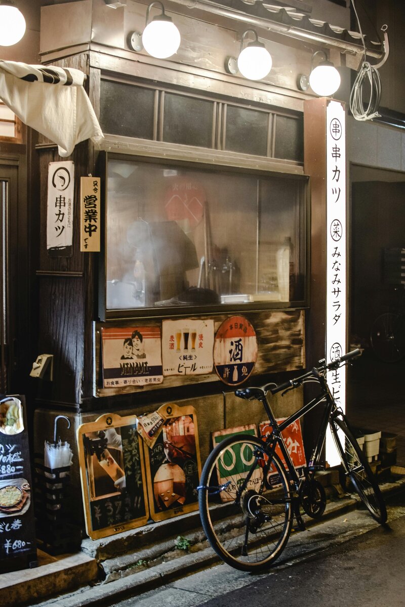 A cozy and authentic Japanese izakaya with warm lighting and a bike parked outside