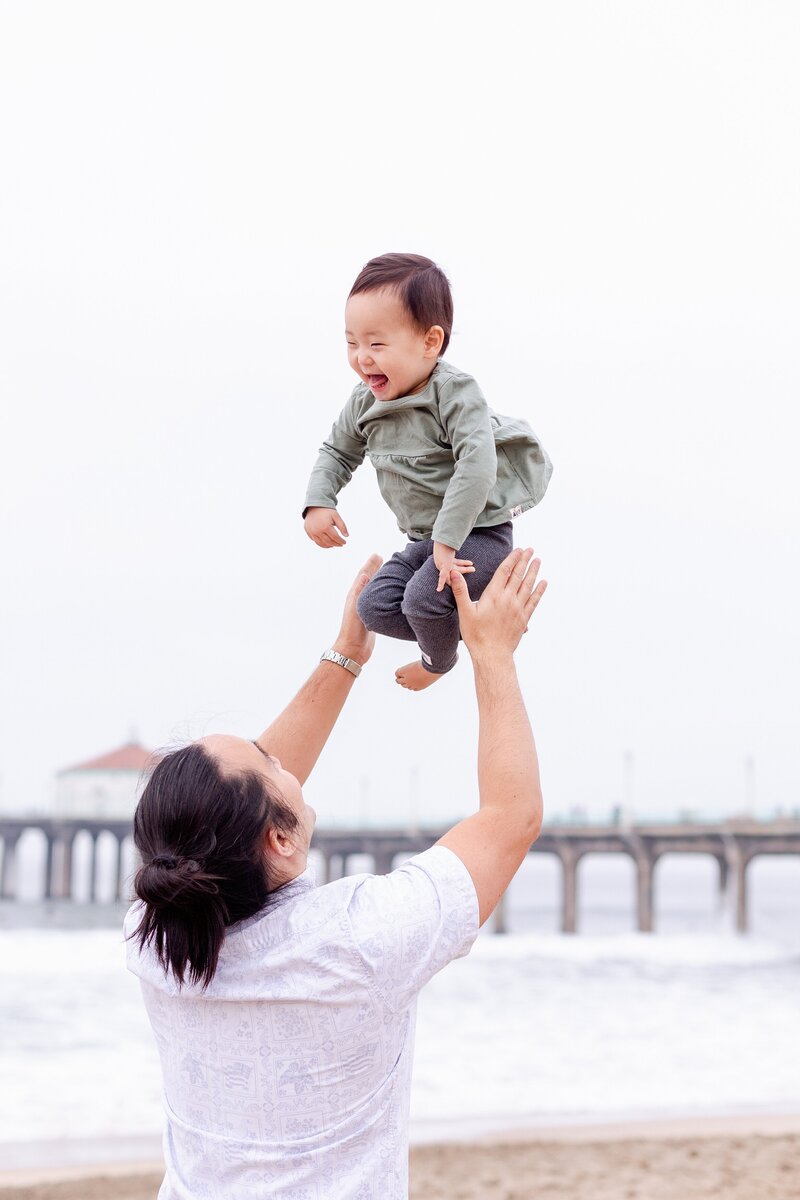 dad tosses baby girl in the air for Southern California family photos
